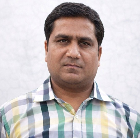manoj sharma | No. 1 Indian Media News Portal Portrait of a man with short dark hair wearing a multicolored plaid shirt, looking at the camera with a neutral expression.