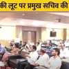 Speaker addressing a conference in a hall as attendees listen; a bold Hindi banner about government funds misuse is visible at the top.