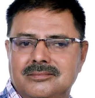 Portrait of a middle-aged man with glasses and a mustache, wearing a plaid shirt, looking at the camera.