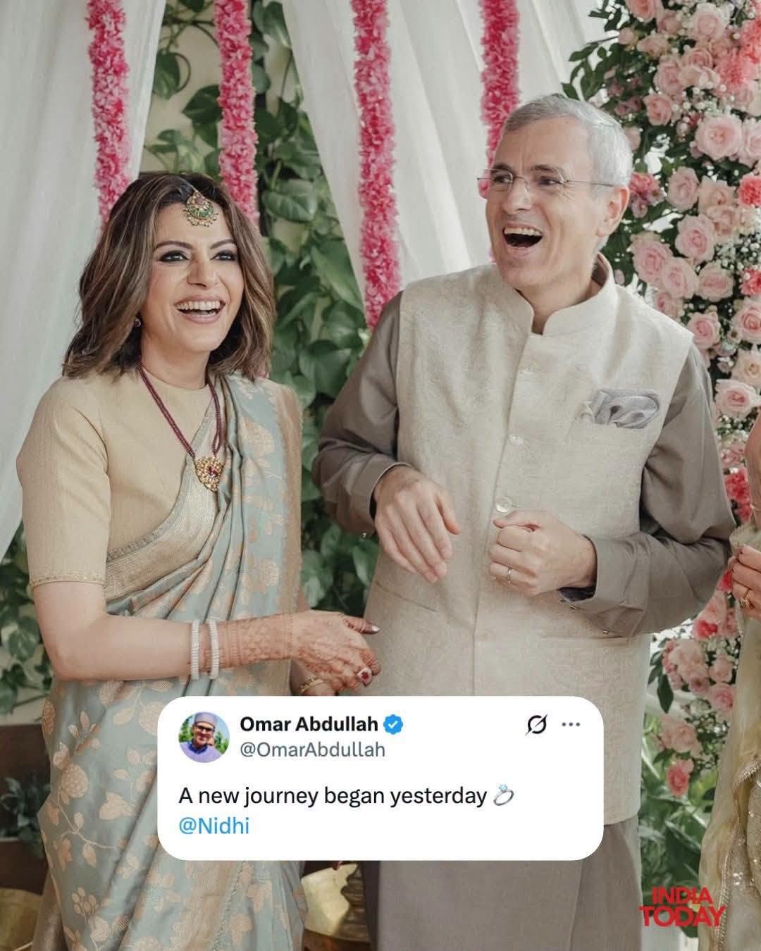 nidhi_omar | No. 1 Indian Media News Portal Joyful Indian couple at a wedding, woman in pale blue saree with mehndi, man in beige kurta, pink floral backdrop and petals framing them.