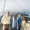 Four adults posing outdoors in a mountainous area, wearing traditional Indian clothing.