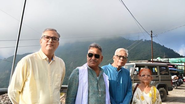 Four adults posing outdoors in a mountainous area, wearing traditional Indian clothing.