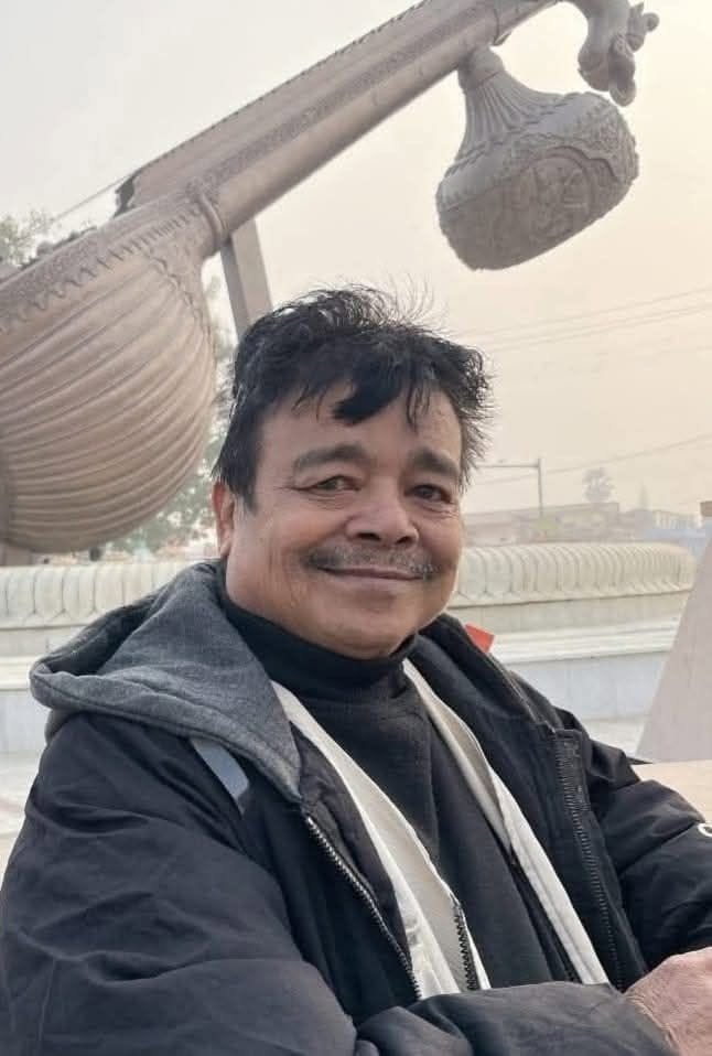 rb_thapa | No. 1 Indian Media News Portal Smiling man in a dark jacket and scarf poses outdoors with a large ornate street-lamp sculpture in the background.