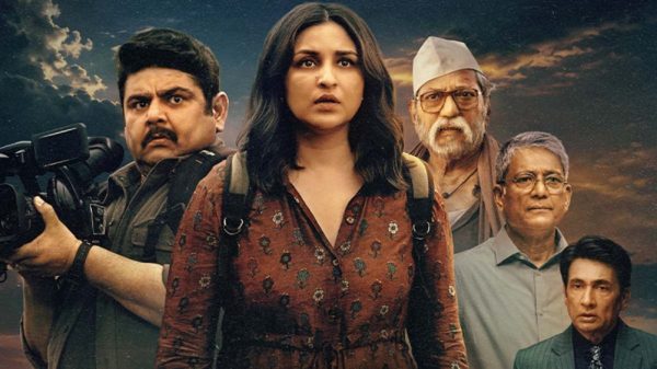 Poster image of five adults with a sunset sky: a woman in a brown floral dress at center, flanked by a cameraman and four men in different outfits, suggesting a film promo.