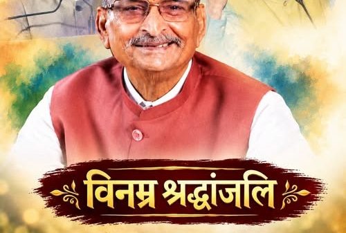 Tribute poster with a smiling man in a red vest, two faded background portraits, a lit lamp and flowers, and the Hindi text 'विनम्र श्रद्धांजलि'.