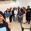 A group of friends posing together for a selfie indoors, smiling and standing in a casual party setting.