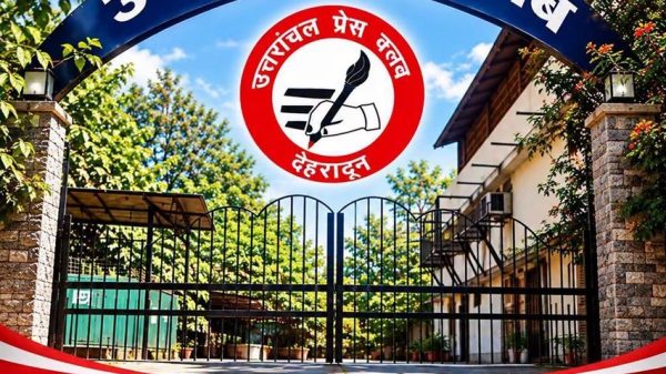 Gate to Uttarakhand Press Club featuring a blue arch sign, a red circular emblem of a hand holding a pen, and bold Hindi text.