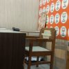Wooden chair at a table in a cafe, with an orange wall covered in white circular logos and a framed picture leaning on the wall.