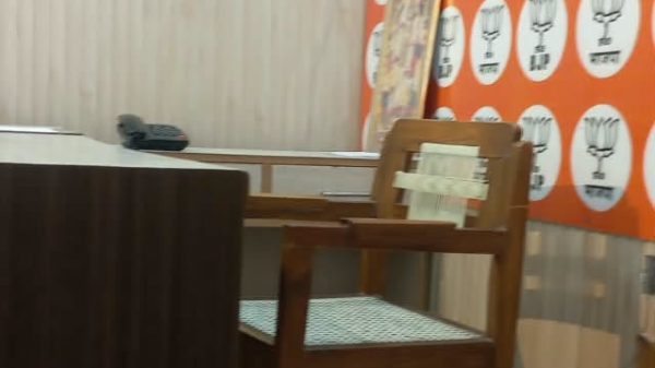 Wooden chair at a table in a cafe, with an orange wall covered in white circular logos and a framed picture leaning on the wall.