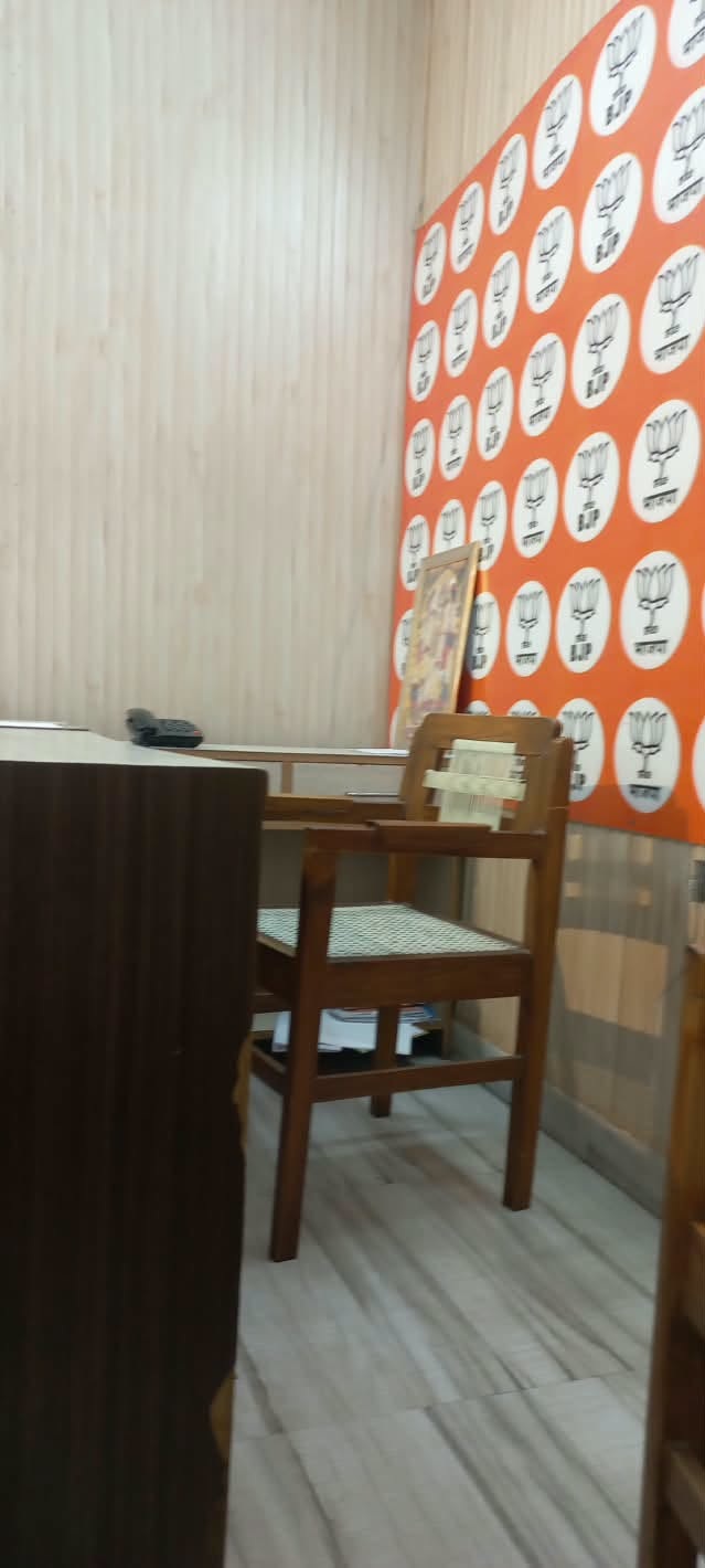 Wooden chair at a table in a cafe, with an orange wall covered in white circular logos and a framed picture leaning on the wall.